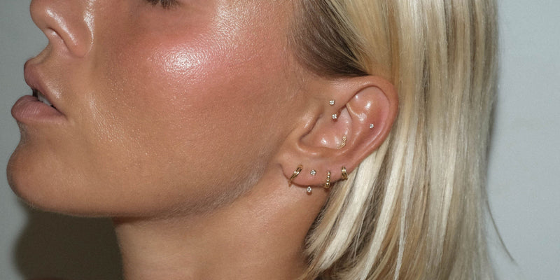 Close-up of a woman's profile with a diamond stud and gold hoops in her ear.