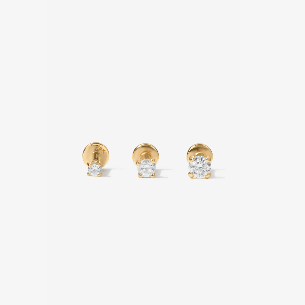 Three gold stud earrings with clear lab diamonds, arranged horizontally on a light gray background.