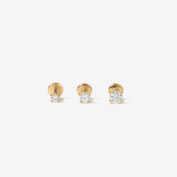 Three gold stud earrings with clear lab diamonds, arranged horizontally on a light gray background.