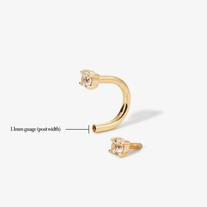 Gold-tone clear-stone U-shaped earring shown with one end detached beside a label.